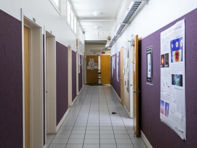 Down the hallway are classrooms and faculty offices. On the walls are student posters and flyers advertising various events going on around campus.