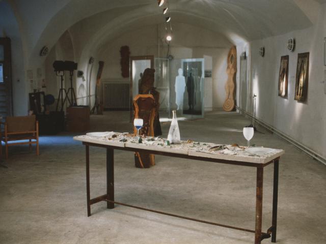 Janna Waldinger: Stůl Nedůvěry ("Table of Distrust"). Glass sculpture "Consciousness," a joint project with Lowell Downey, is shown in the background; Photo Credit: Janna Waldinger